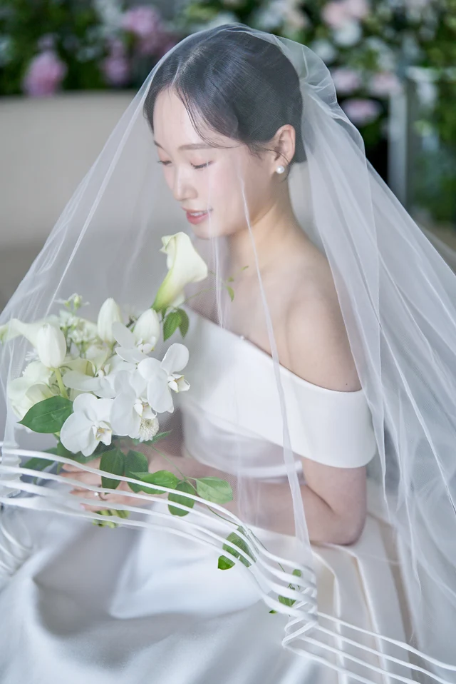 베일 너머 부케를 든 신부의 자연스러운 표정